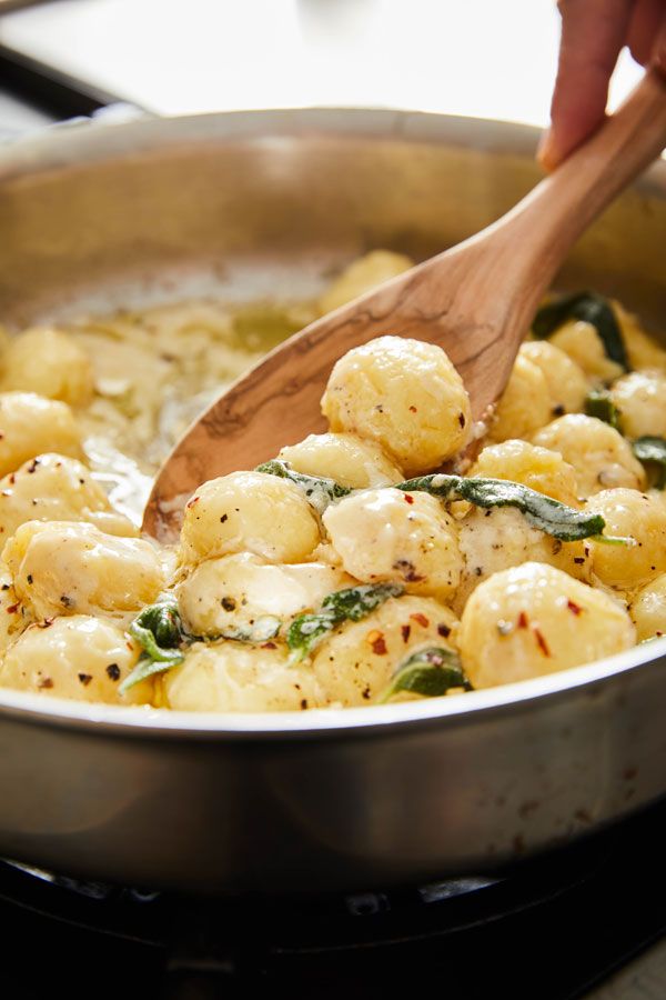 a wooden spoon is being used to stir some food in a pan on the stove