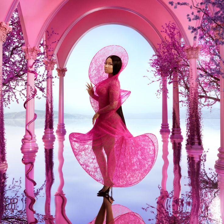 a woman in a pink dress and hat is standing under an archway with trees reflected in the water