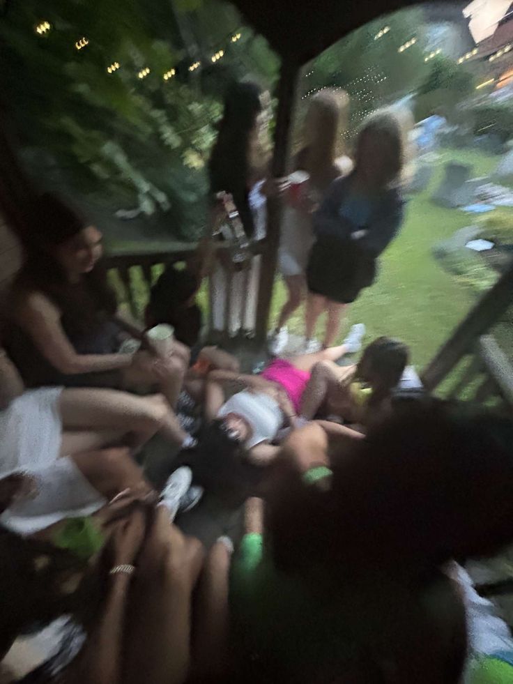 a group of people sitting on top of a wooden bench next to each other in the grass