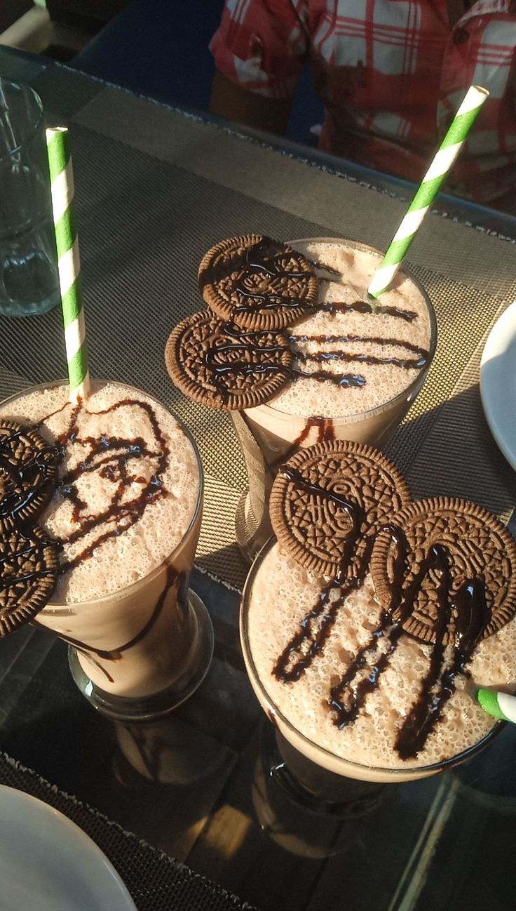 three iced drinks with chocolate drizzle and oreo cookies on the rims