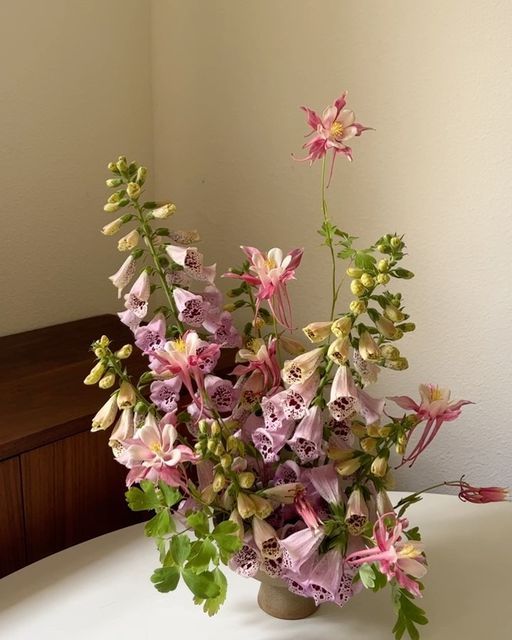 a vase filled with lots of flowers on top of a white tablecloth covered table