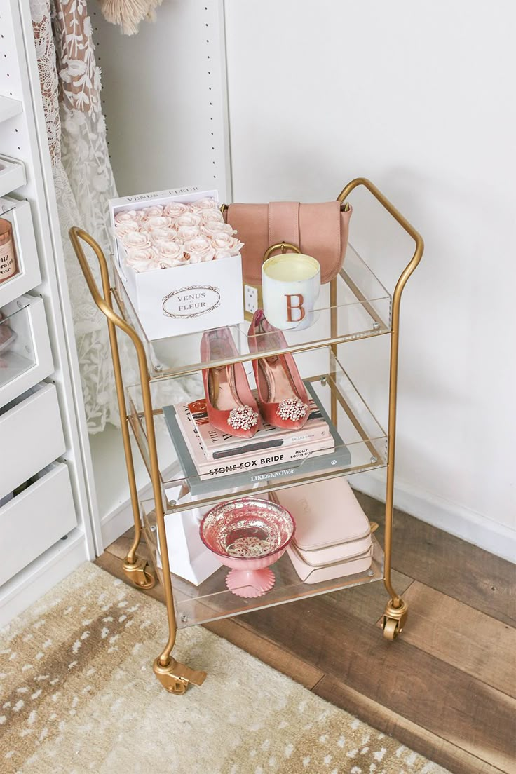 a gold metal cart with shoes on it in front of a closet full of items