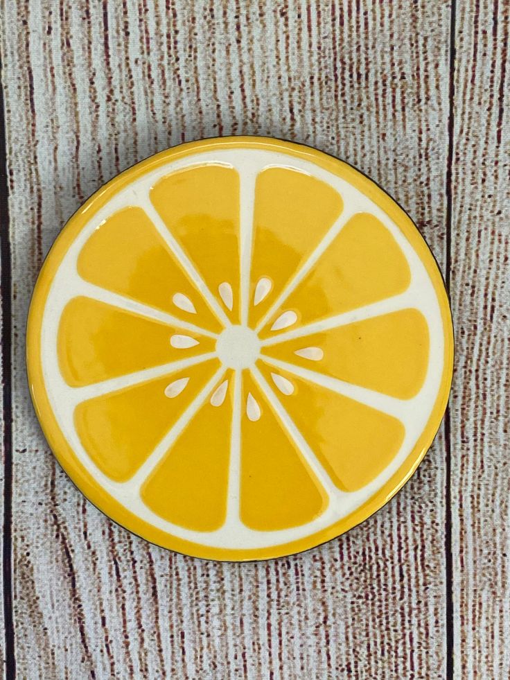 a yellow and white plate sitting on top of a wooden table covered in orange slices