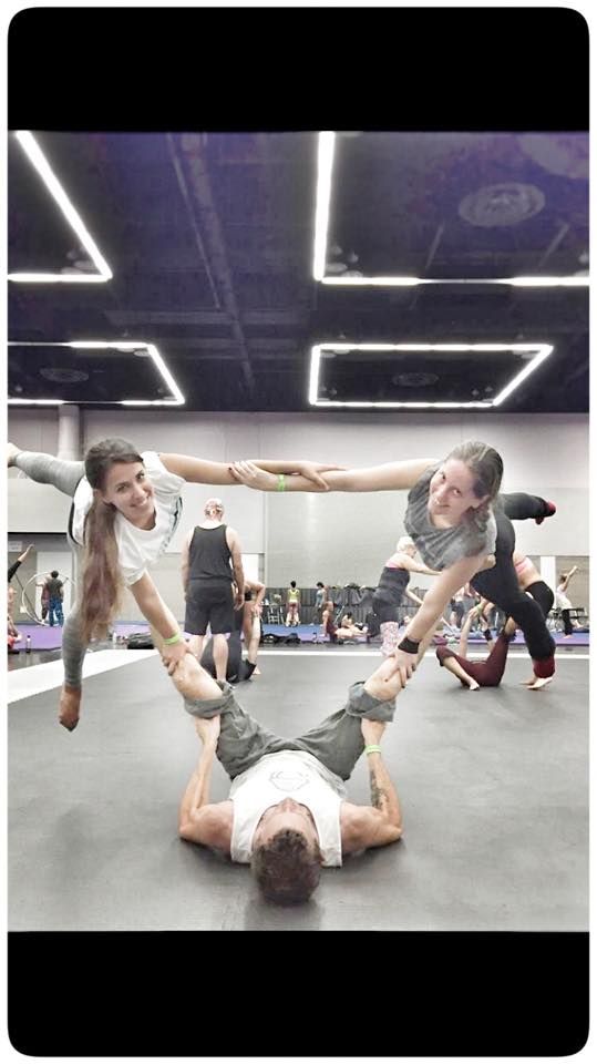 a group of people standing around each other on top of a gym floor with one person upside down