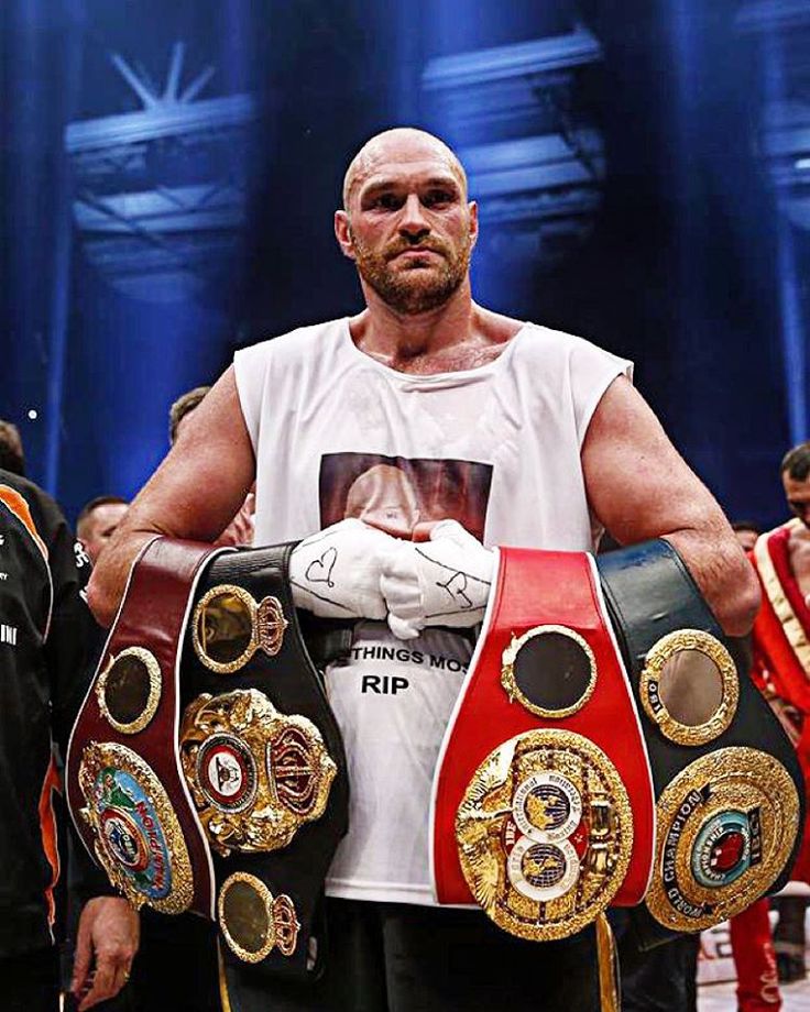 a man holding two boxing belts in his hands