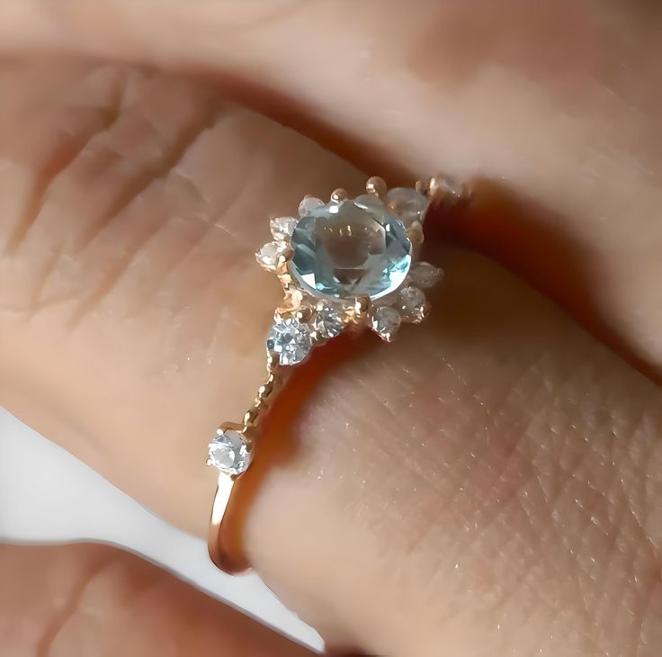 a woman's hand holding a ring with an aqua topazte and diamond accents