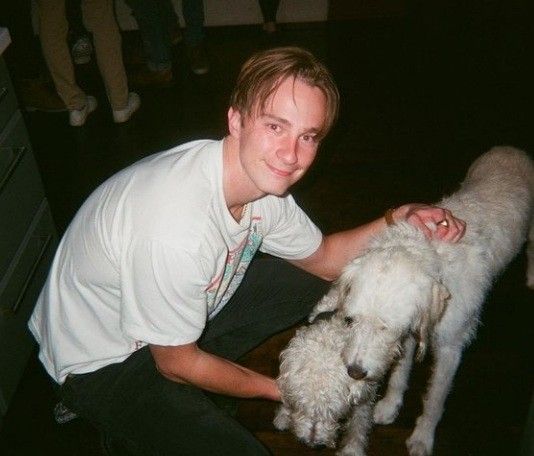 a man petting a white poodle on the nose