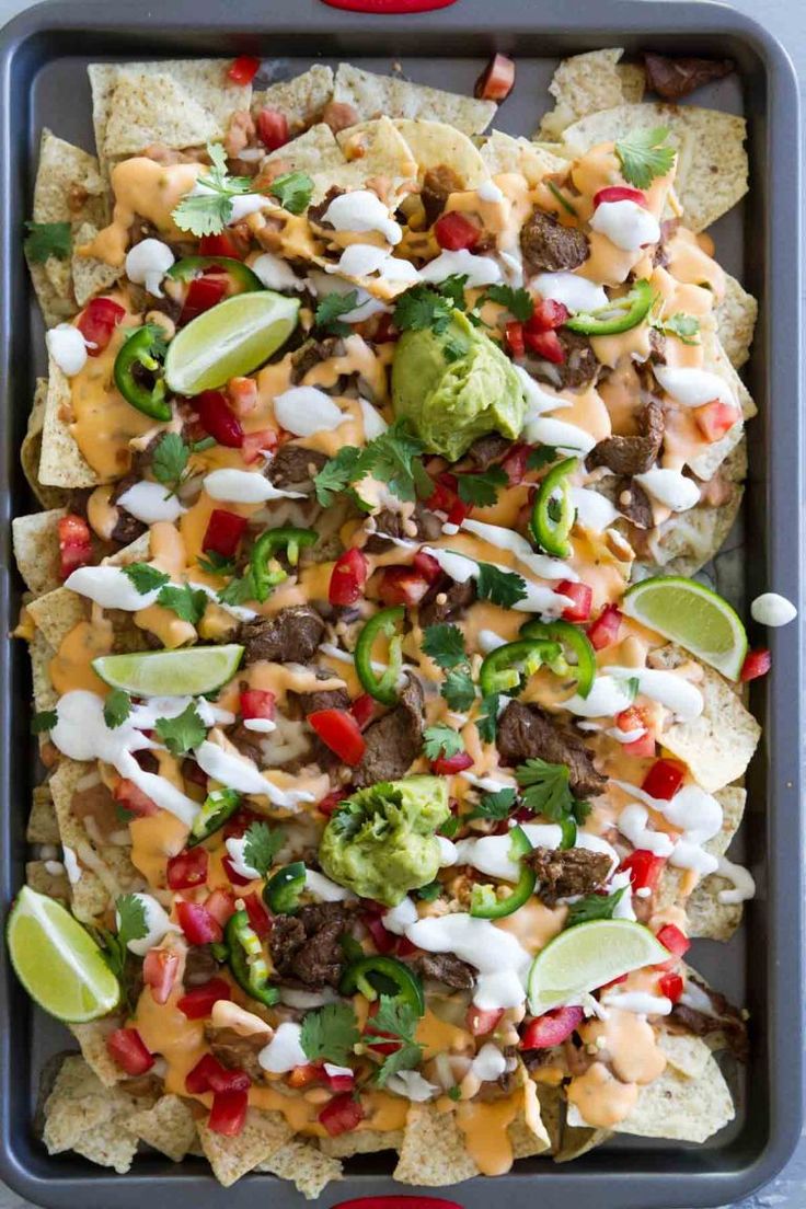 a tray filled with nachos topped with cheese, meat and veggies