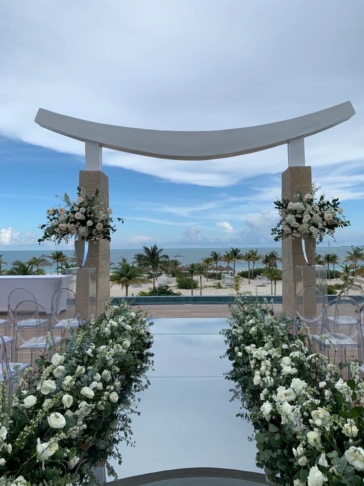 an outdoor ceremony setup with white flowers and greenery on the aisle, overlooking the ocean