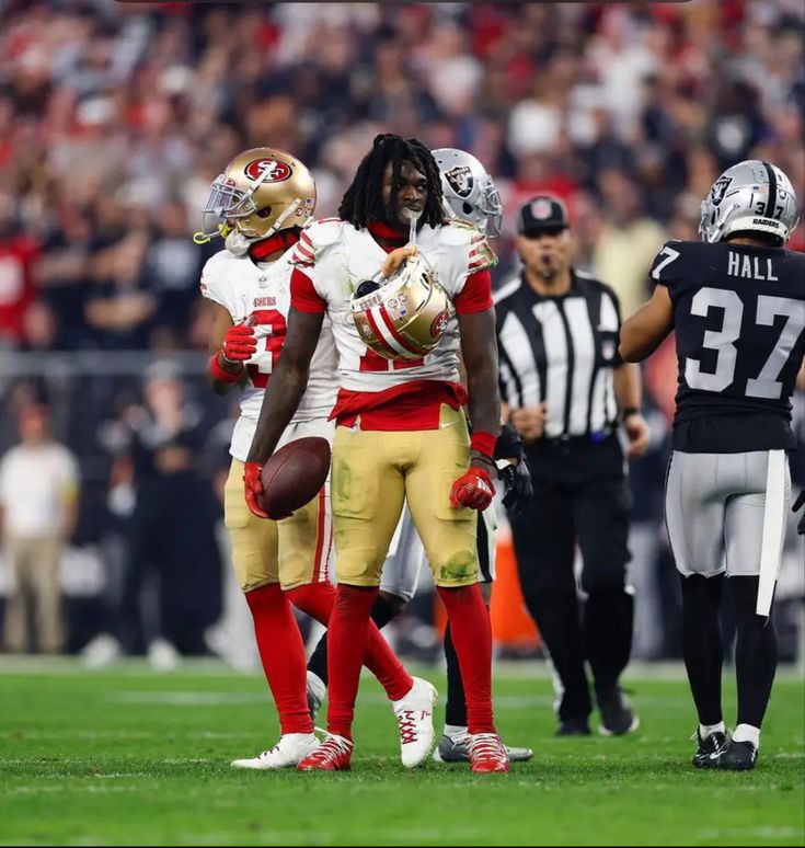 two football players standing on top of a field next to an official referee and some fans