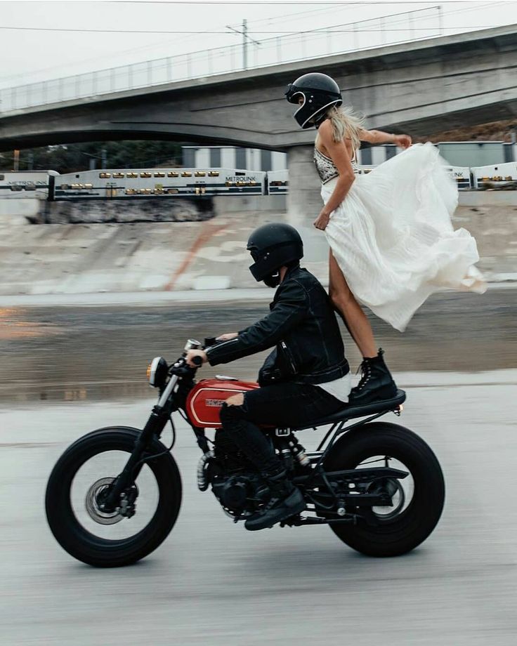 a man riding on the back of a motorcycle next to a woman in a white dress