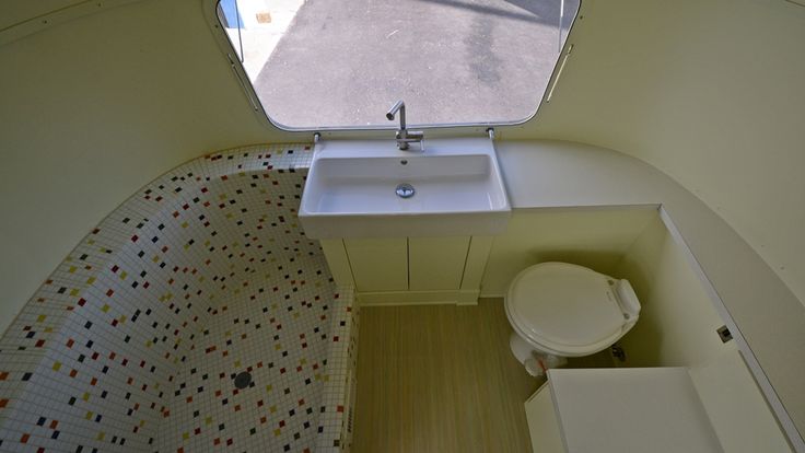 a small bathroom with a sink, toilet and window in the corner on the wall