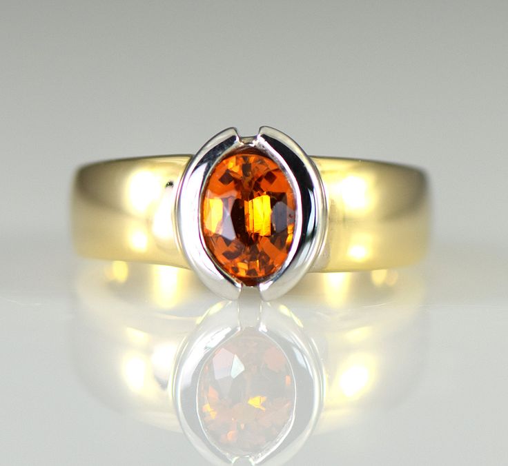 A brilliant orange gem Spessartite Garnet is semi bezel set in 14k white gold with a wide yellow gold shank. Spessartite, a rare form of garnet, also called mandarin or Malaya garnet, ranges from a yellow-orange through brilliant orange to orange-red. They combine very good hardness with excellent brilliance and sparkle. Spessartite is found in Africa and like all garnets is untreated. Garnet is January's birthstone and the 2nd wedding anniversary gemstone. The spessartite garnet is an 8 x 6 mm Fine Jewelry Orange Sapphire Anniversary Ring, Modern Orange Gemstone Rings, Orange Sapphire Ring For Anniversary, Orange Fine Jewelry With Polished Finish, 14k Gold Jewelry With Orange Center Stone, 14k Gold Orange Jewelry With Polished Finish, Orange 14k Gold Jewelry With Polished Finish, Orange 14k Gold Jewelry With Center Stone, Orange Sapphire Ring For Formal Occasions