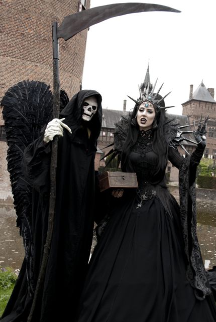 two people dressed up as witches in front of a castle