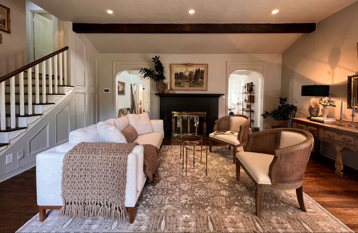 a living room filled with furniture and a fire place under a stair bannister