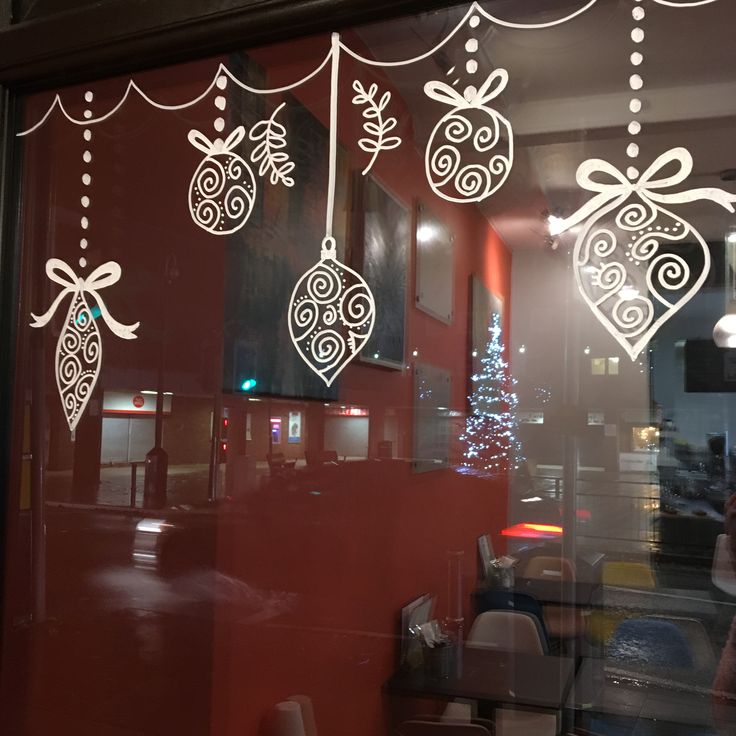 the window is decorated with christmas decorations and ornaments hanging from it's glass door