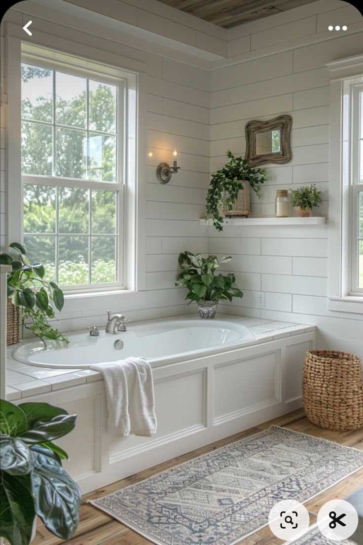 a bathroom with a bathtub, rug and plants in the window sill next to it