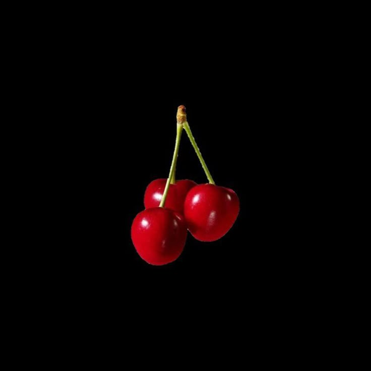 three cherries hanging on a black background