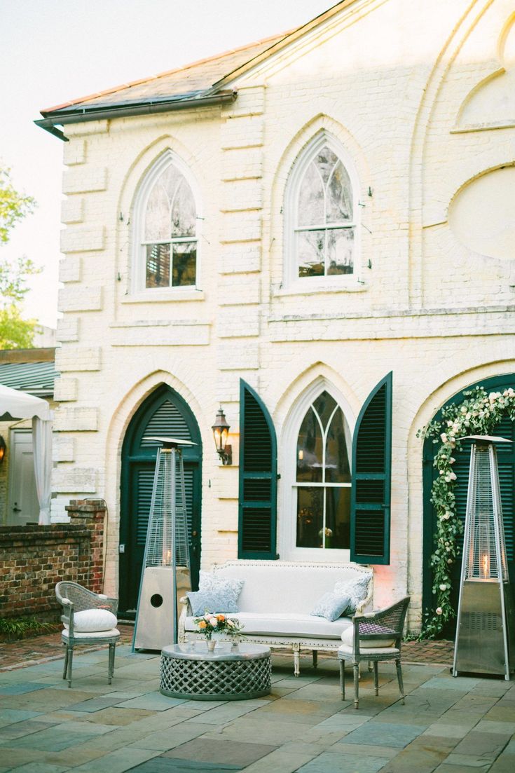 a white couch sitting on top of a stone floor next to a tall brick building