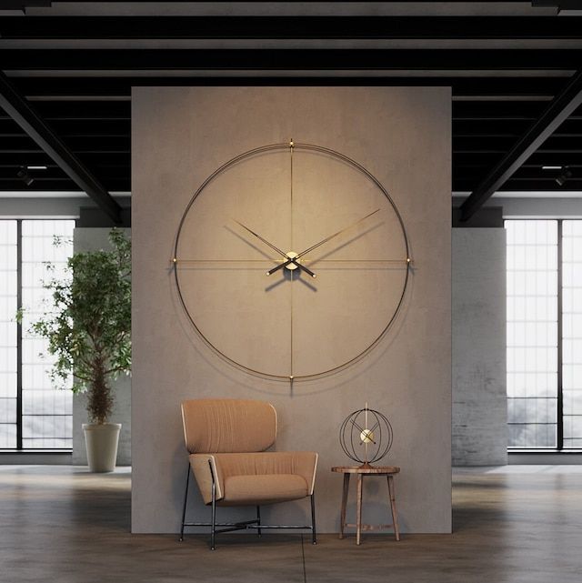 a large clock mounted to the side of a wall next to a chair and table