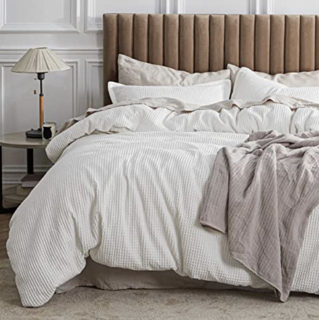 an unmade bed with white sheets and pillows