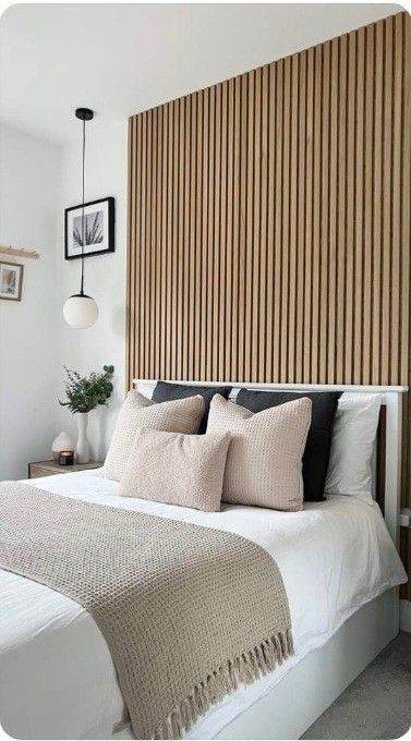 a bed with pillows and blankets on top of it next to a wooden headboard