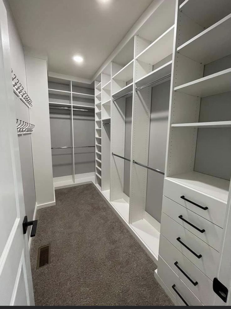 an empty walk in closet with lots of shelves and drawers on the wall, along with carpeted flooring