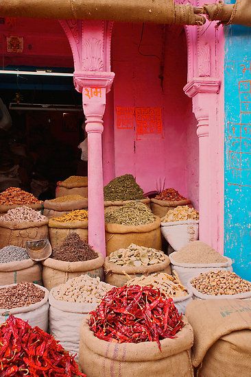 an outdoor market with lots of different types of food in baskets and bags on the ground