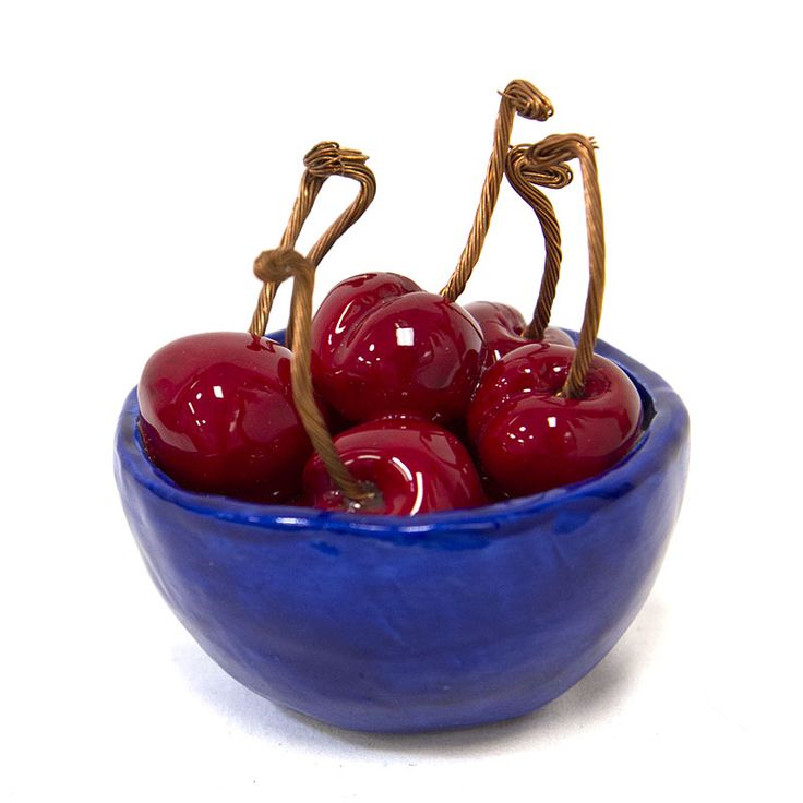 a blue bowl filled with cherries on top of a white table