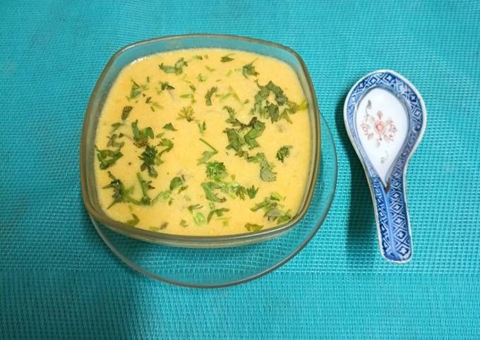 there is a bowl of soup and a spoon on the blue tablecloth next to it