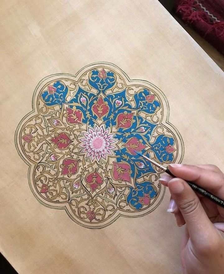 a person is drawing on a piece of wood that has been decorated with flowers and leaves