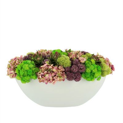 a white bowl filled with lots of green and pink flowers