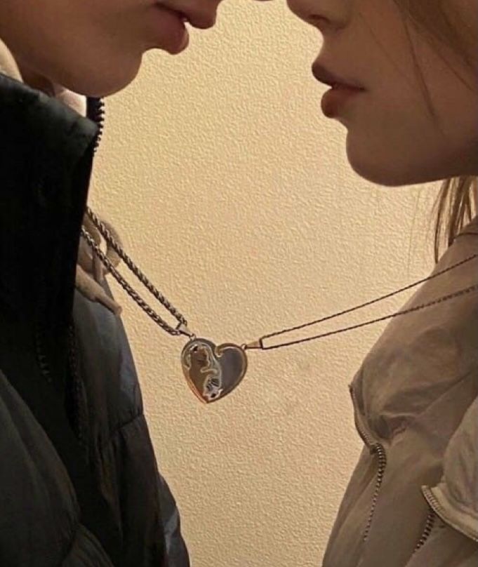 two people standing next to each other and one has a heart shaped necklace on his neck