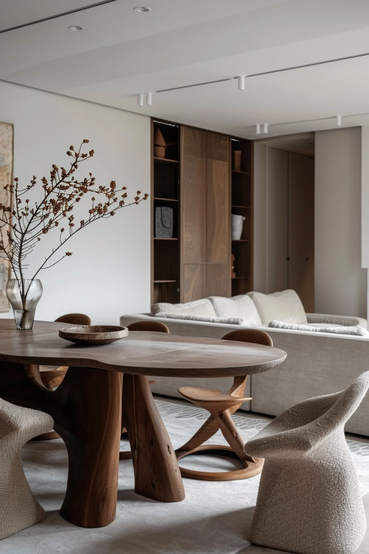 a living room filled with furniture and a wooden dining table surrounded by white couches