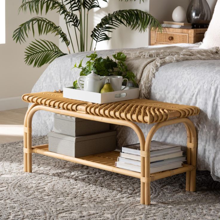 a wicker coffee table sitting on top of a bed next to a potted plant