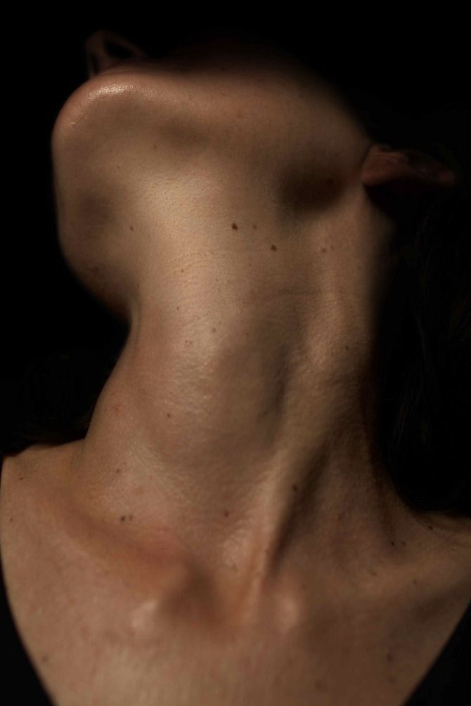 the back of a woman's neck is shown in this dark photo with light coming from behind it