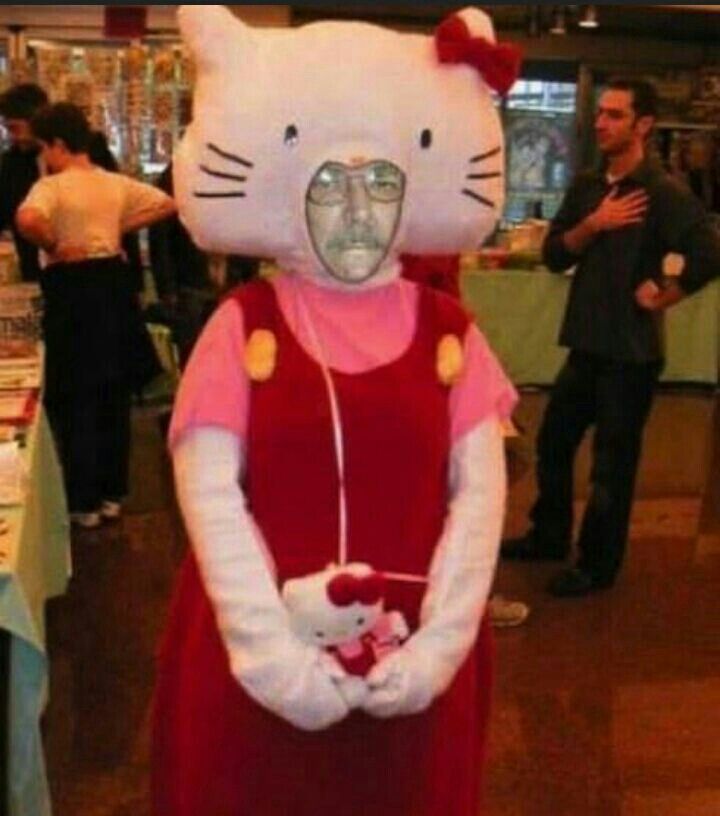 a person in a hello kitty costume standing next to a table with other people around