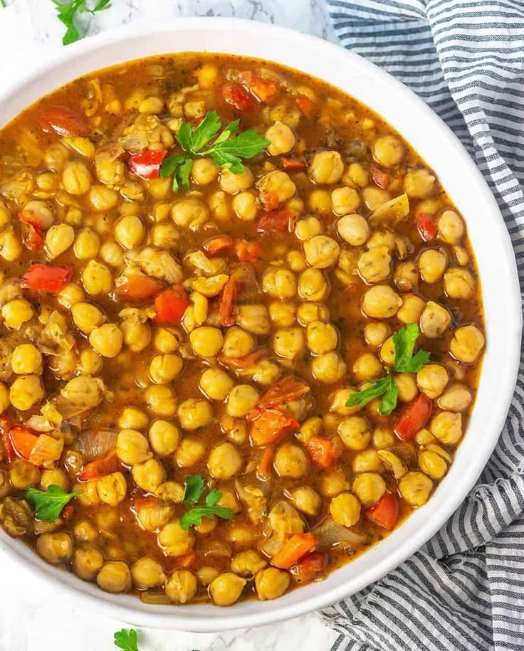 a white bowl filled with chickpeas and garnished with fresh parsley