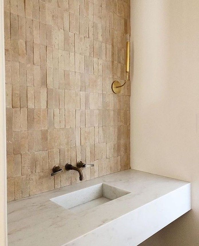 a white sink sitting under a bathroom mirror next to a wall mounted faucet