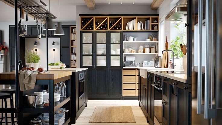 an open kitchen with black cabinets and wooden flooring is pictured in this image from the hallway