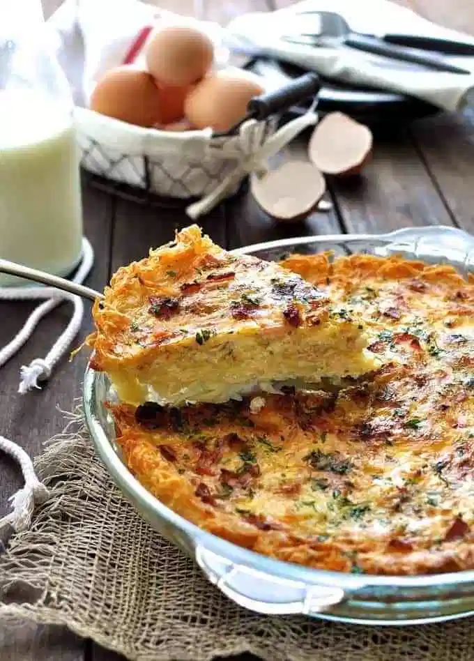 two pieces of quiche sitting on top of a table next to eggs and utensils