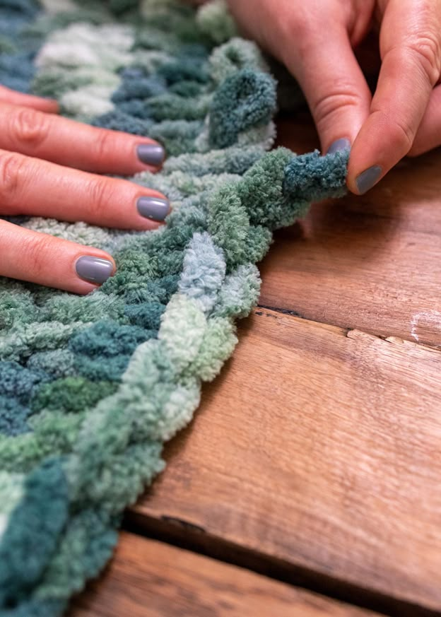 two hands with manicures on their nails are touching the edge of a rug