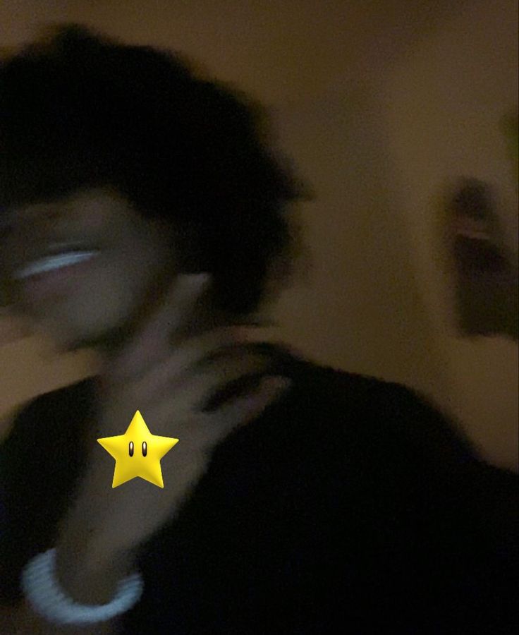 a blurry photo of a person holding a cell phone to their face with a yellow star on it