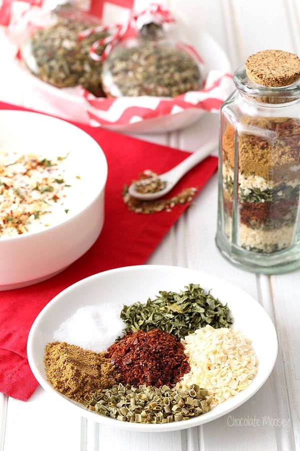 two bowls filled with spices on top of a red table cloth next to a glass jar