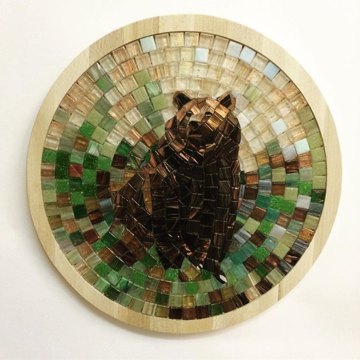 a bear made out of mosaic tiles in a circular frame on a white wall or floor