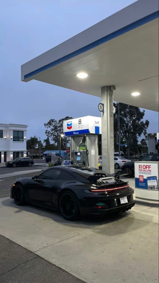 a black sports car parked at a gas station