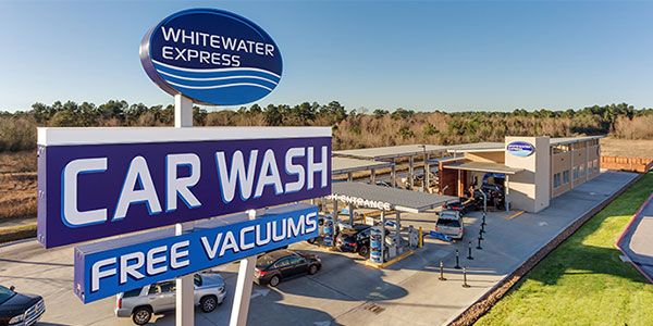 a car wash and free vacuums sign in front of a building with cars parked outside