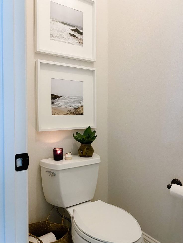 a white toilet sitting in a bathroom next to a wall mounted art above it's tank