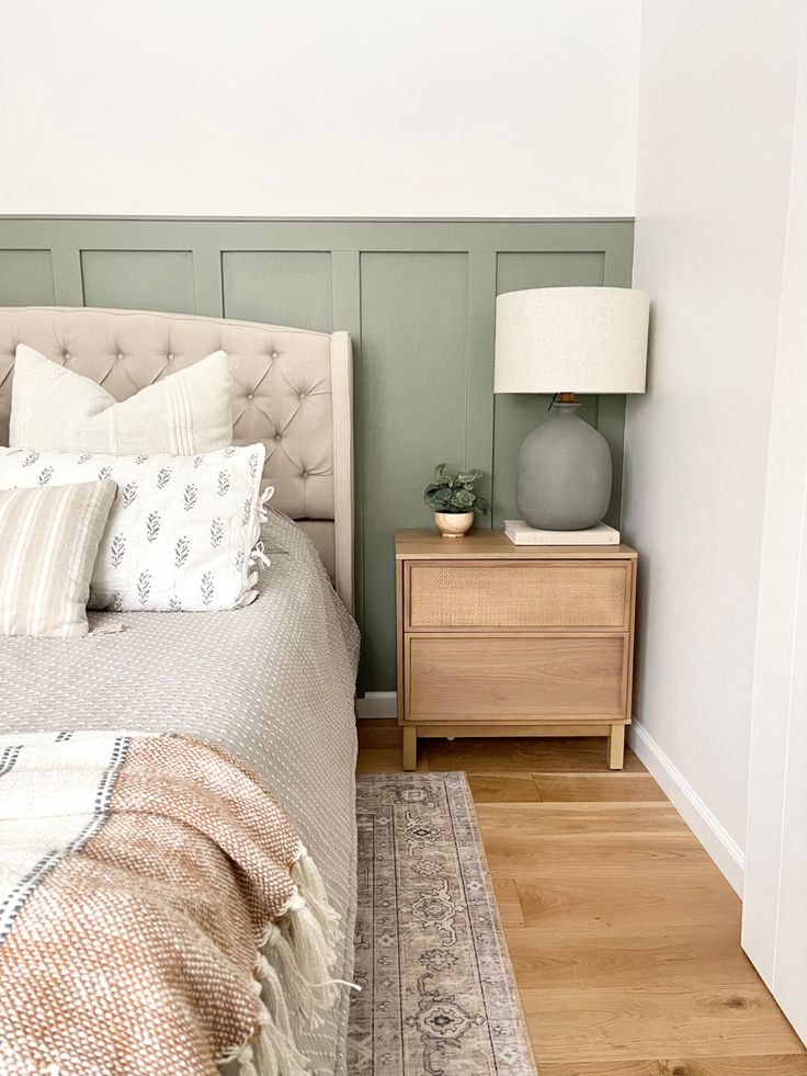 a bed sitting next to a nightstand with a lamp on top of it in a bedroom