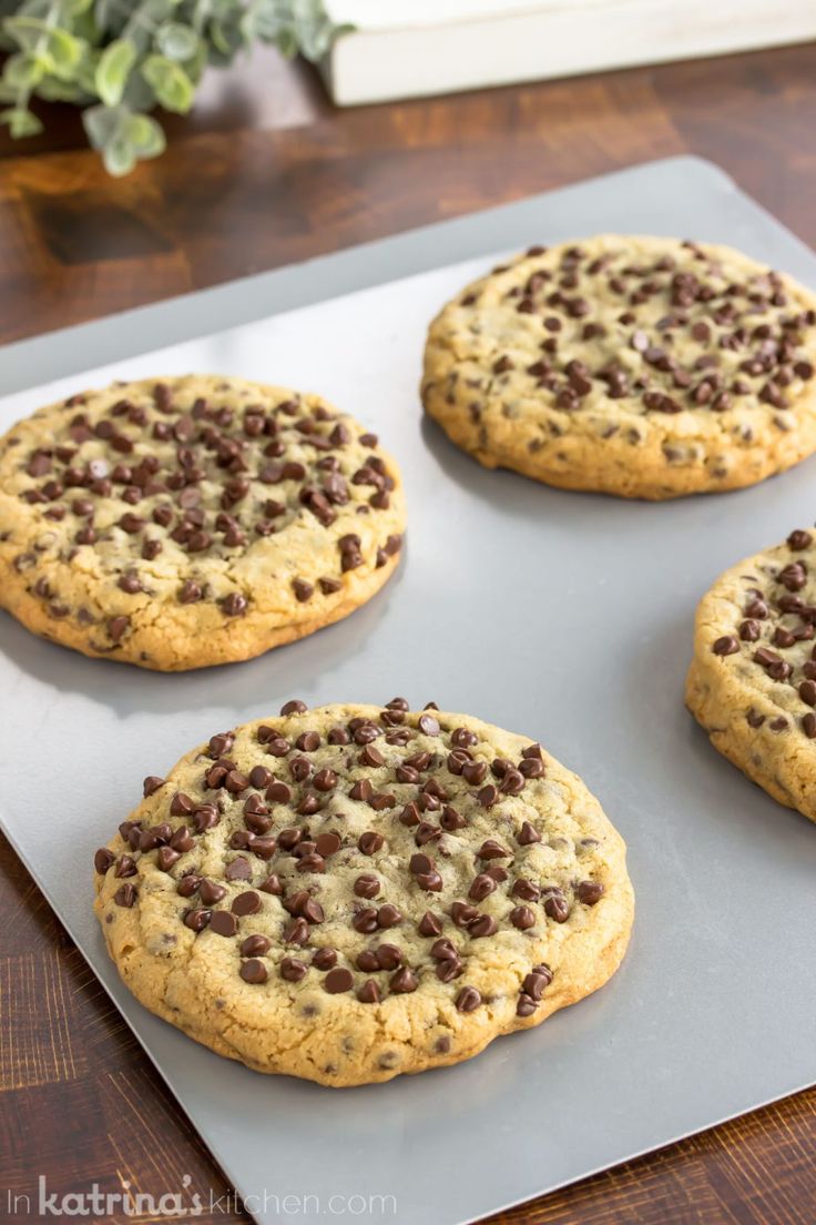 four chocolate chip cookies sitting on top of a cookie sheet